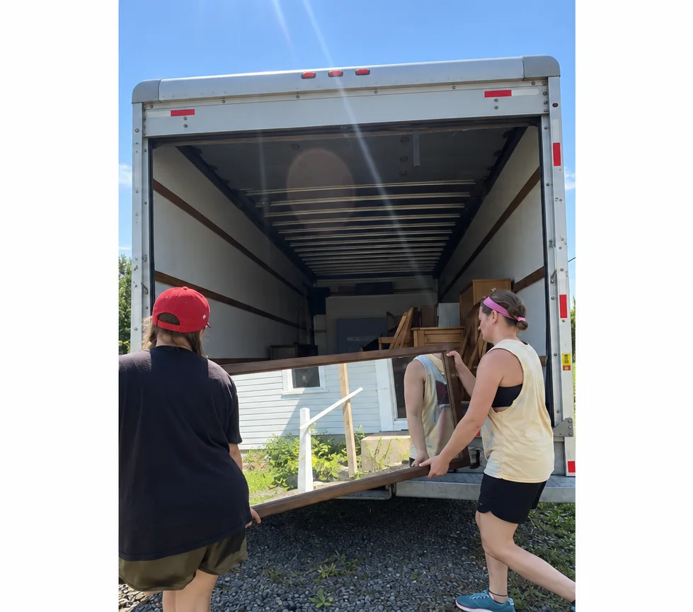 Movers carefully handling a large wooden armoire